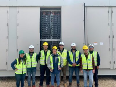 Group of Chilean engineers pose for a photo in-front of a battery storage Vistra’s Moss Landing Energy Storage Facility